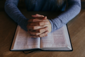 Hands folded on top of a bible