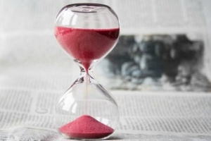 Hourglass filled with red sand on a newspaper
